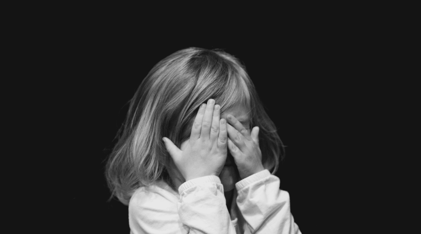 little girl covering face with hands
